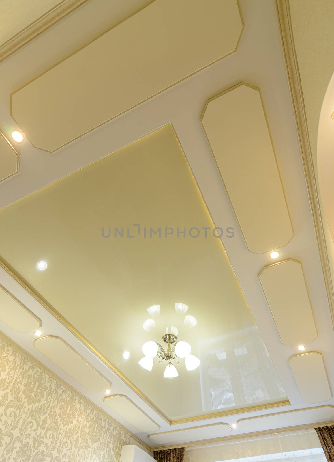 Original stylish multi-level ceiling in gold tones in the bedroom