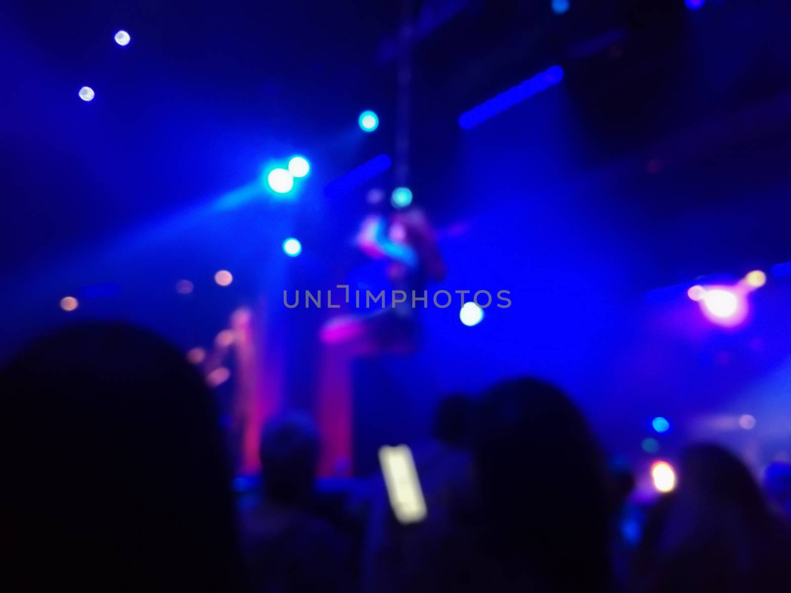 Defocused abstract blurred scene of musical light performance in a concert on stage with crowd