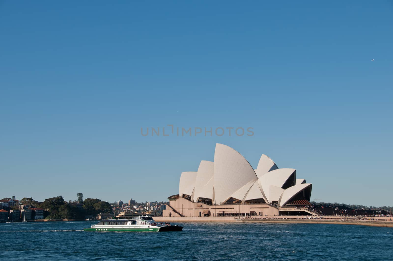 SYDNEY, AUSTRALIA - MAY 5, 2018: Sydney Opera House with famous Sydney city ferry in late afternoon and blue sky.