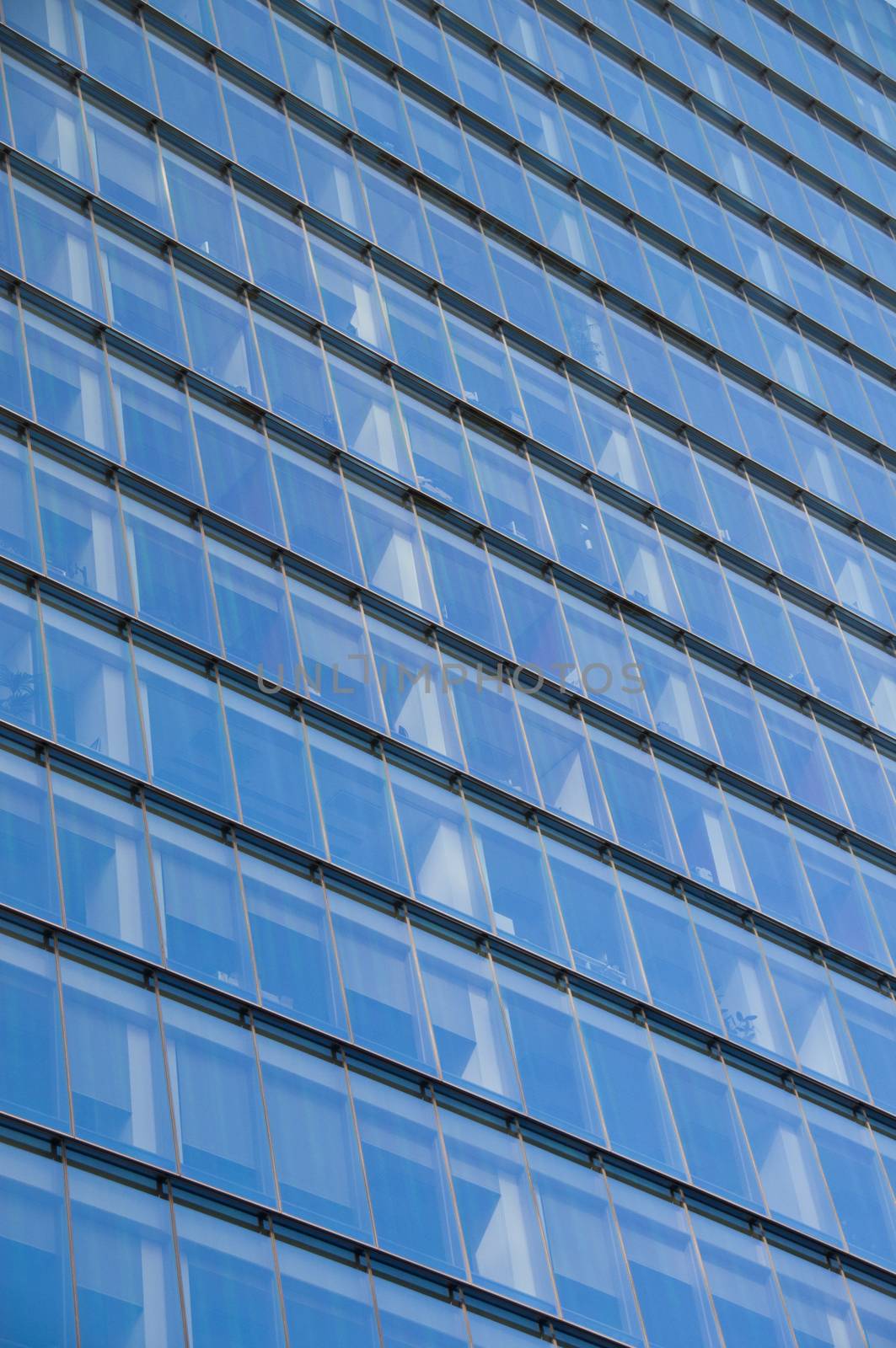 Reflection of blue clear sky on a high-rise skyscraper corporate office building