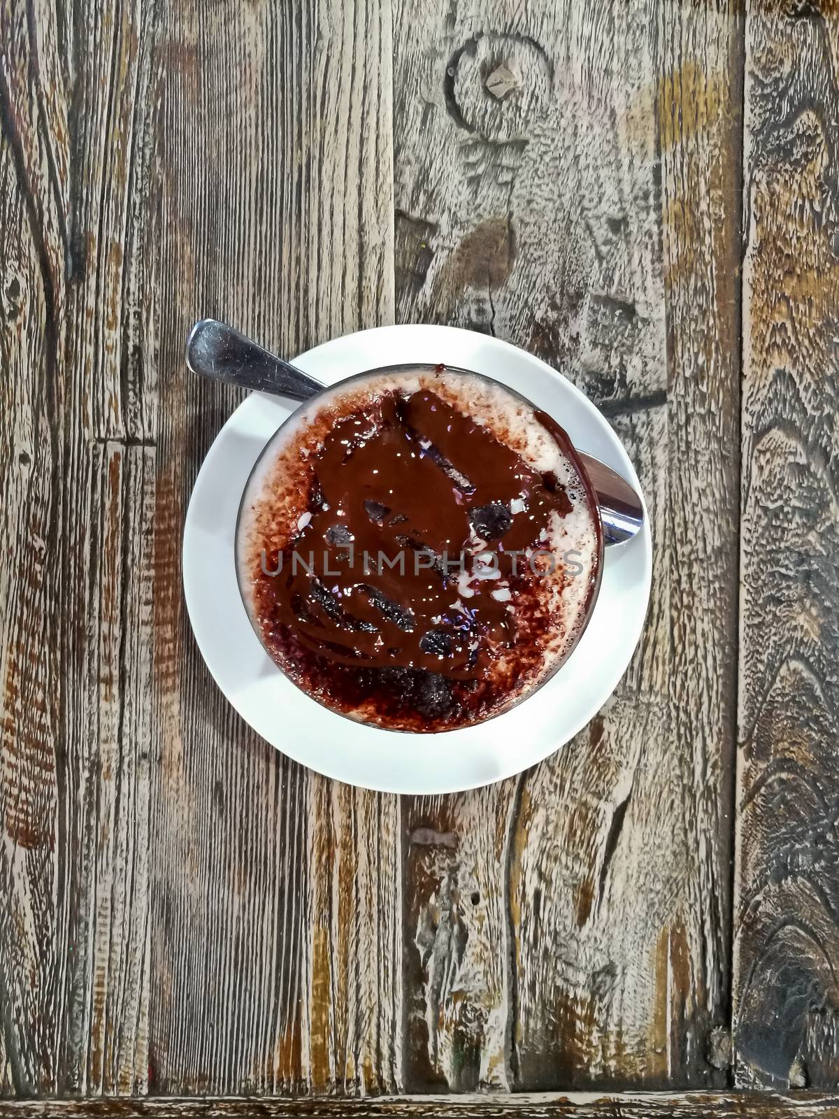 Top view of sweet dark warm hot chocolate on wooden brown table with a spoon