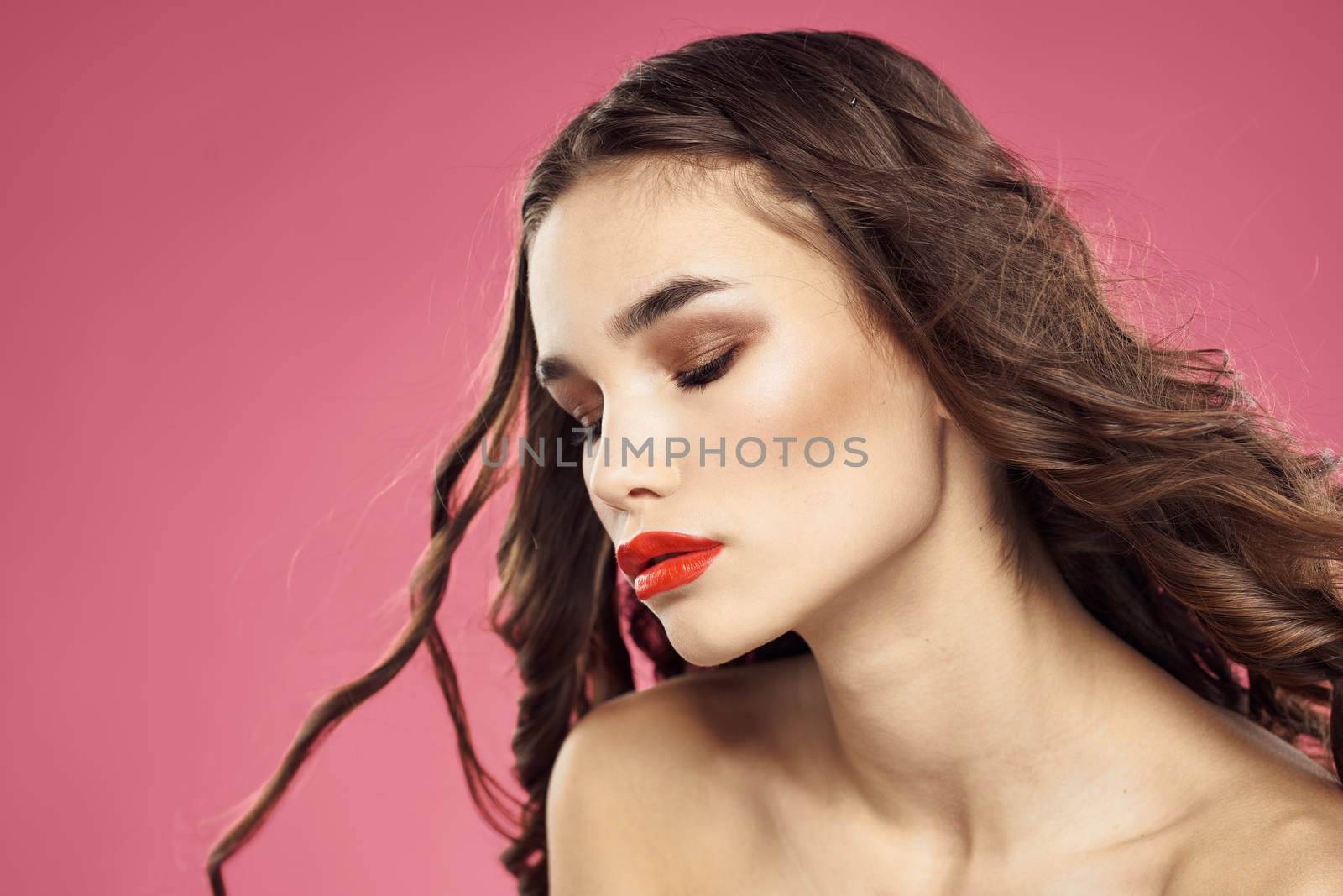 Attractive woman fashionable hairstyle bared shoulders and red lips pink background. High quality photo