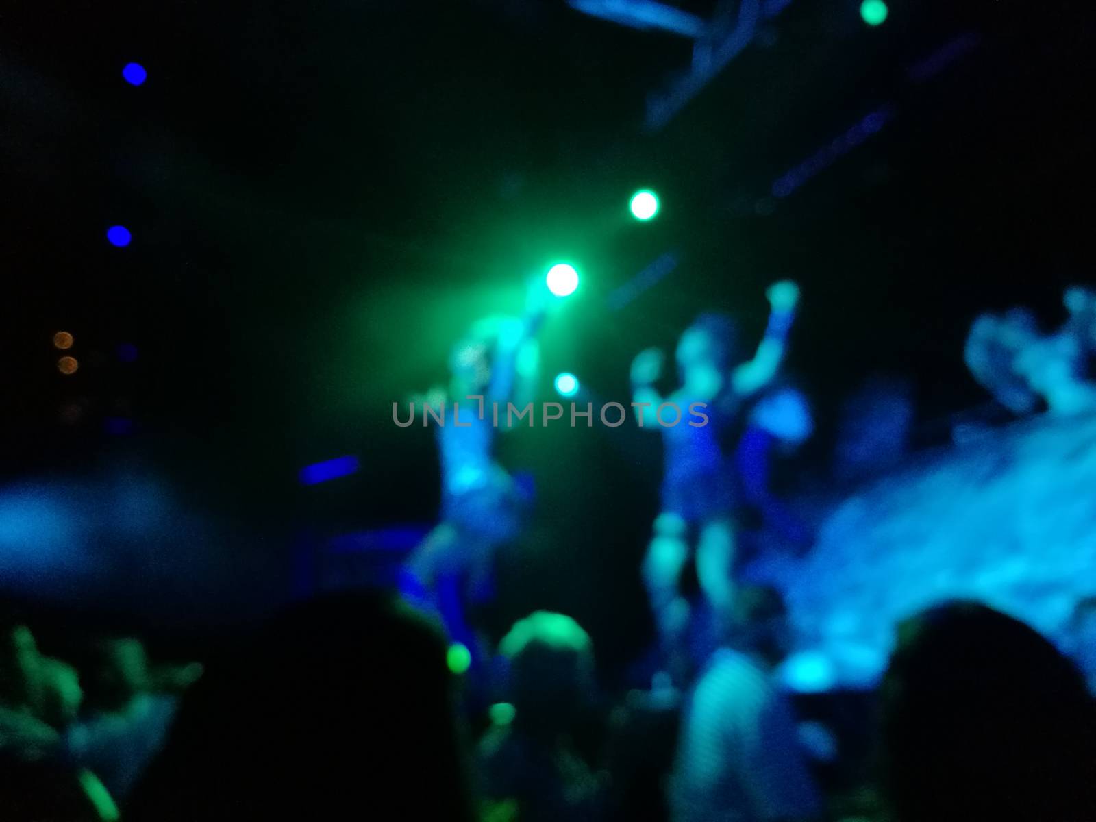 Defocused abstract blurred scene of musical light performance in a concert on stage with crowd