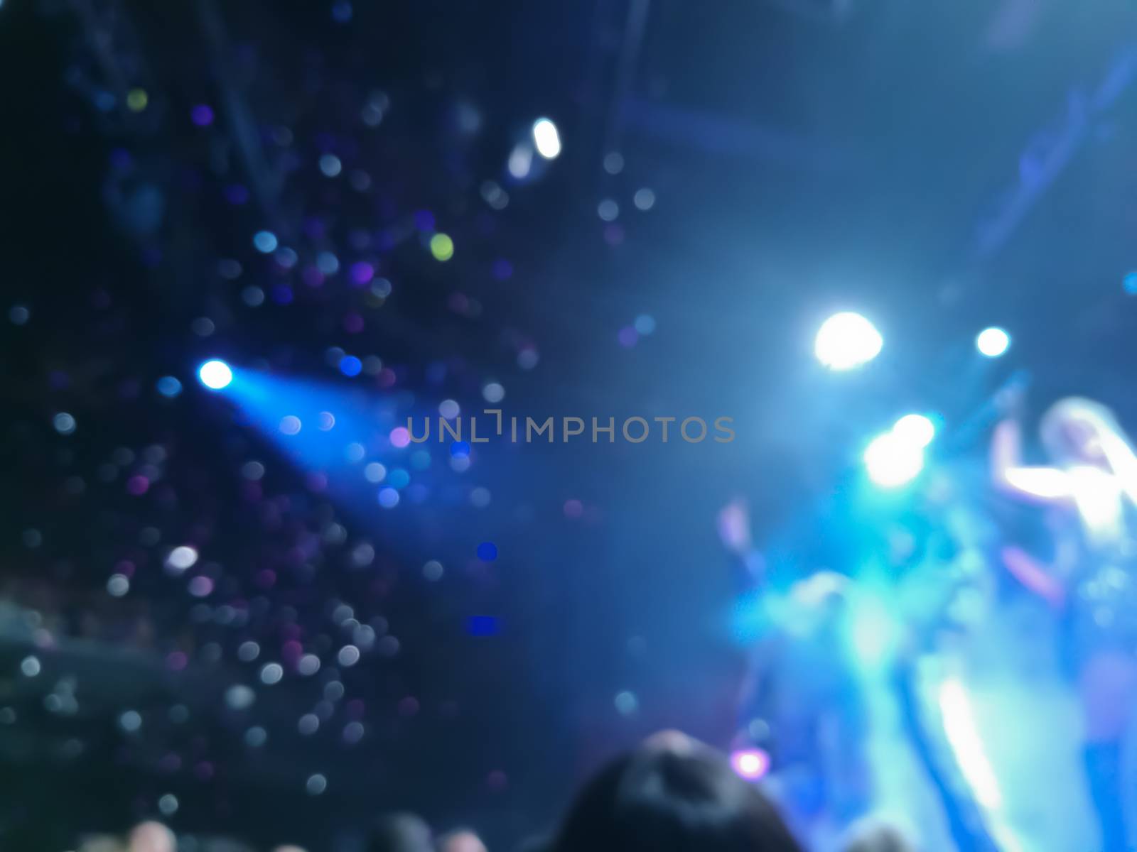 Defocused abstract blurred scene of musical light performance in a concert on stage with crowd