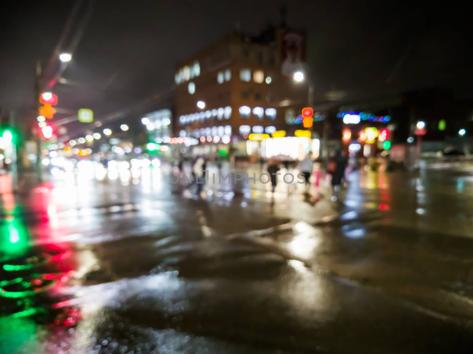 defocused night rain city street view with cars crossing road.