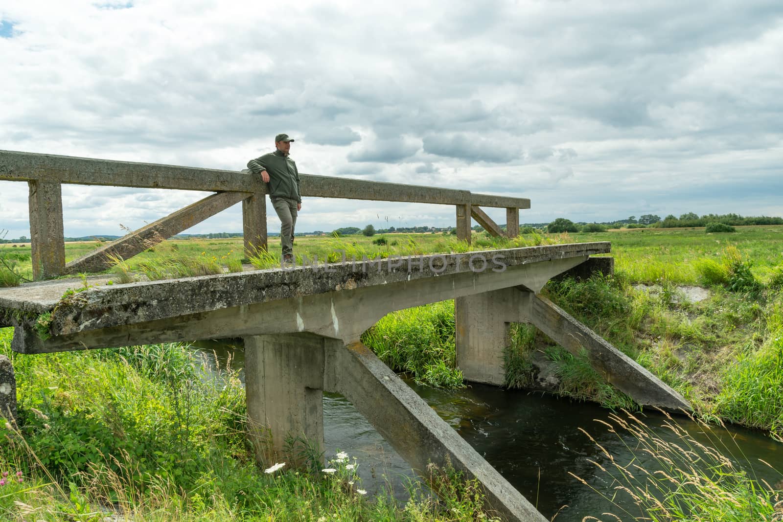 A man standing on an old bridge and looking away, summer river view