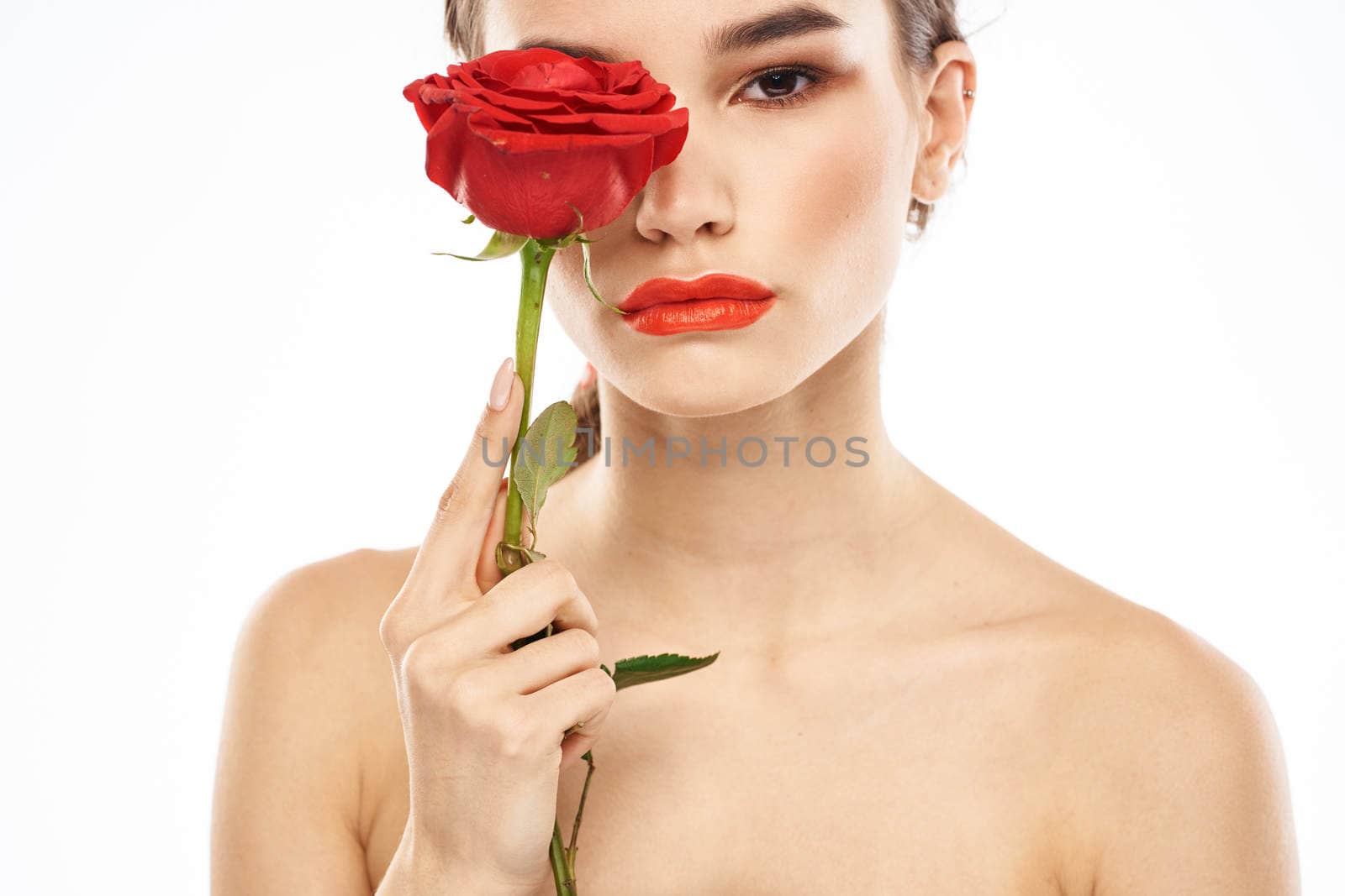 charming brunette girl with makeup on her face and a red rose in her hand. High quality photo
