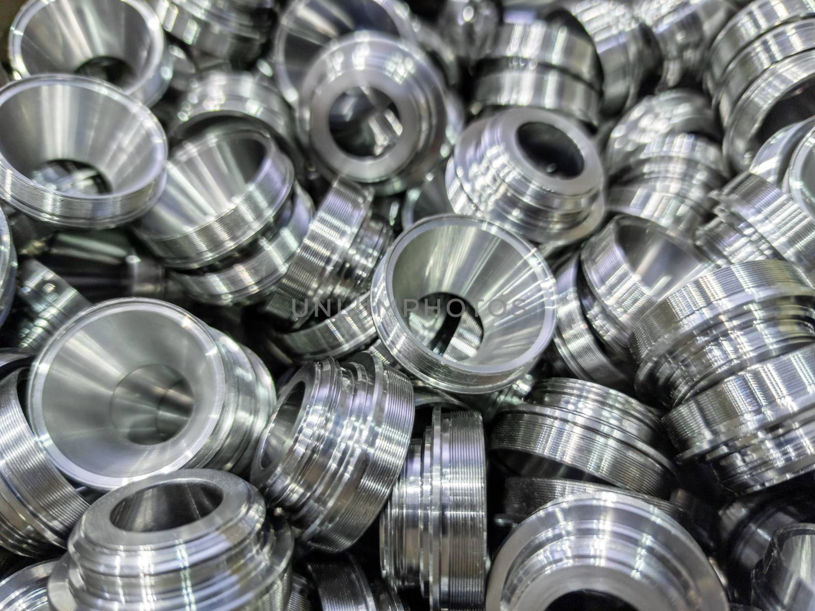 a pile of shiny metal cnc aerospace funnel shape parts production - close-up with selective focus for full frame industrial background