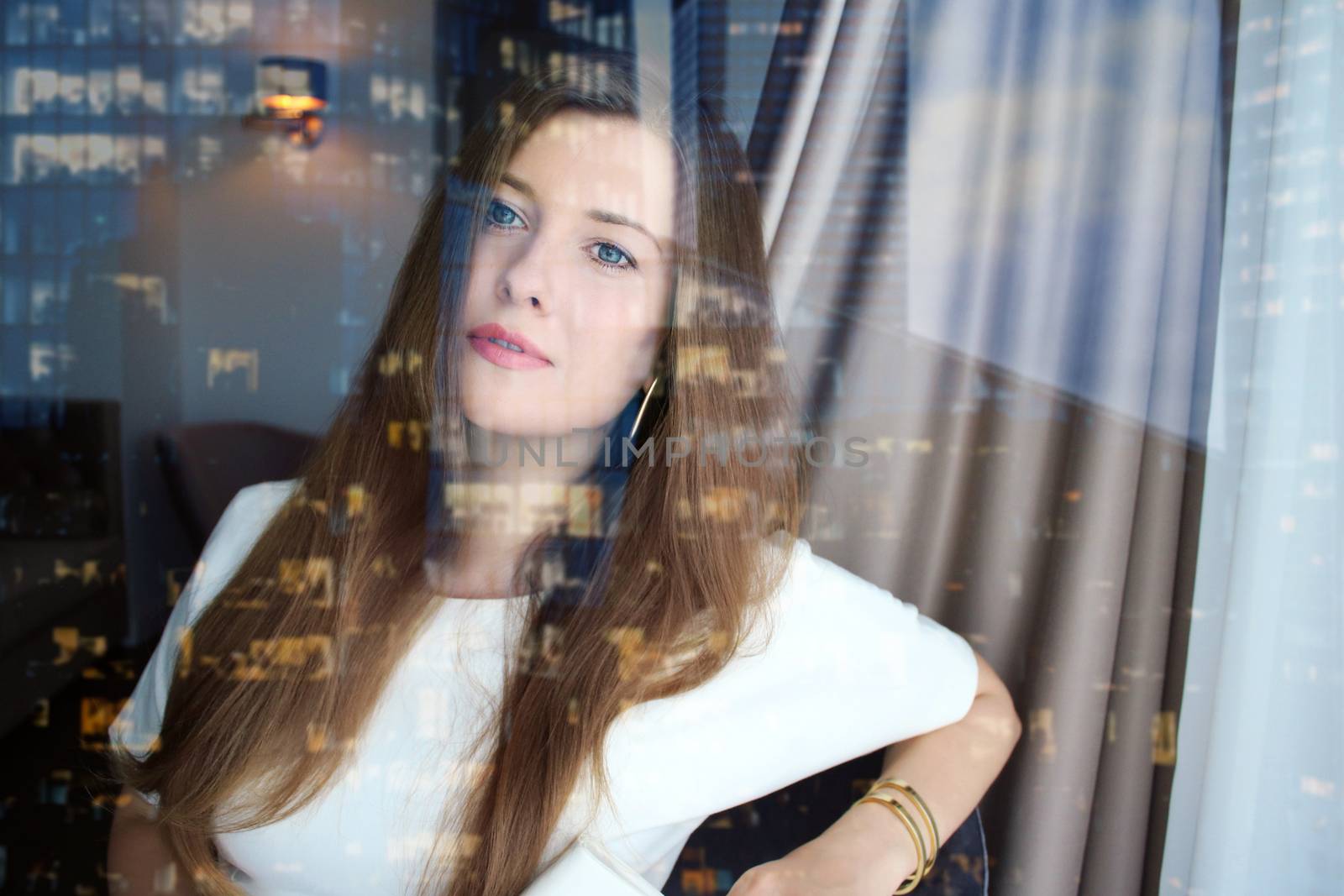 Chic business woman looking out the office window in downtown, w by Anneleven