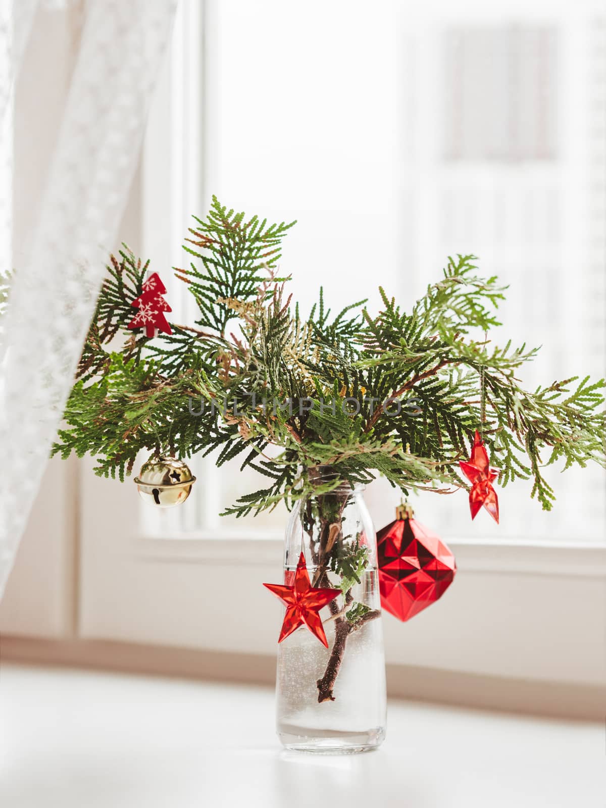 Vase with decorated thuja branches stands on window sill. Sustainable alternative for Christmas tree. Caring for nature. Refusal to cut down spruce forests. New Year celebration.