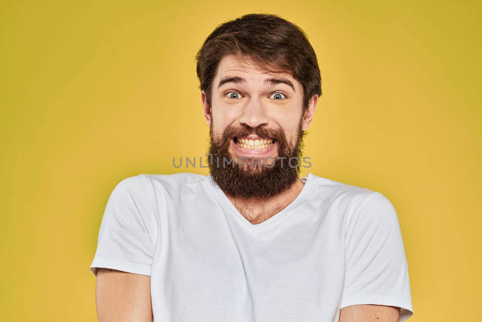 Bearded man in white t-shirt emotions close-up fun yellow background. High quality photo