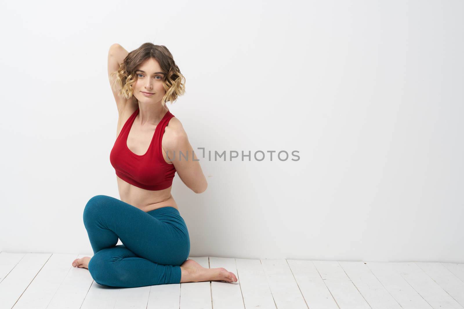 woman doing yoga full length indoors blue leggings red tank top. High quality photo