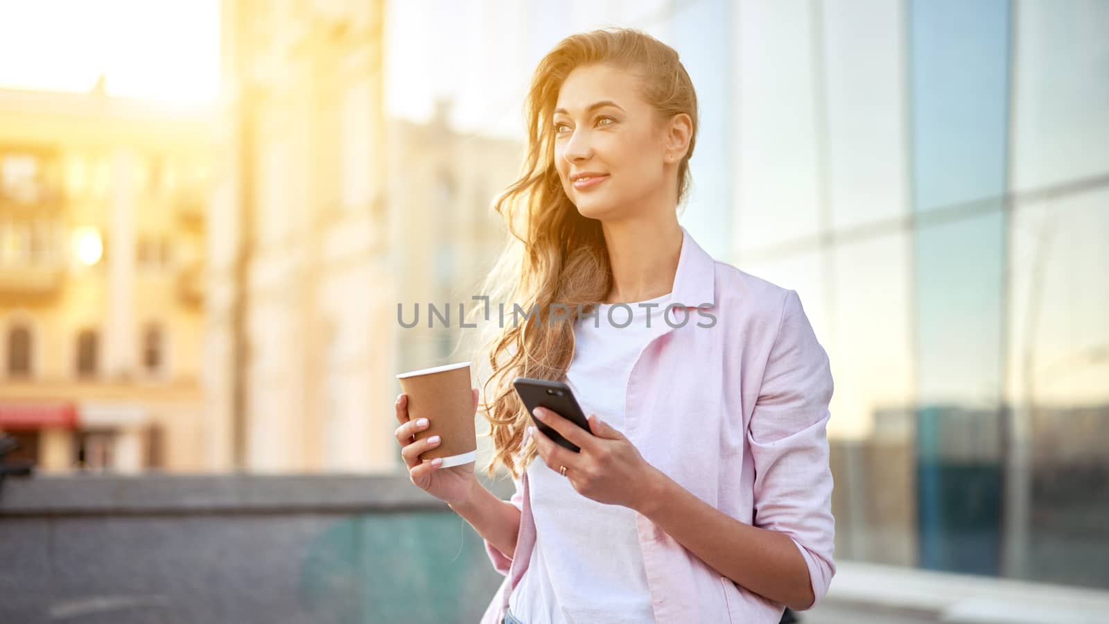 Businesswoman standing summer day near corporate building using smartphone teeth smiling Business person Outdoors Successful european caucasian woman freelancer dressed white shirt pink jacket