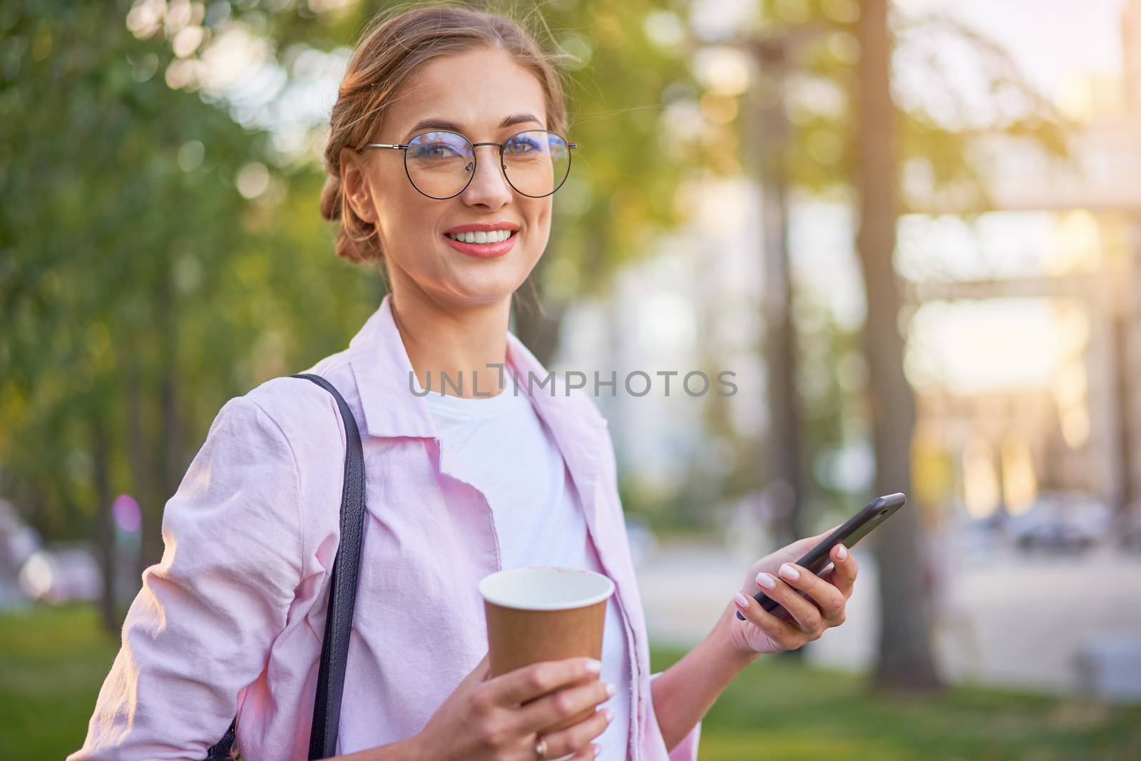 Businesswoman standing summer park Business person using smartphone Outdoors Successful european caucasian woman freelancer or teacher walking outside backpack dressed jeans white shirt pink jacket