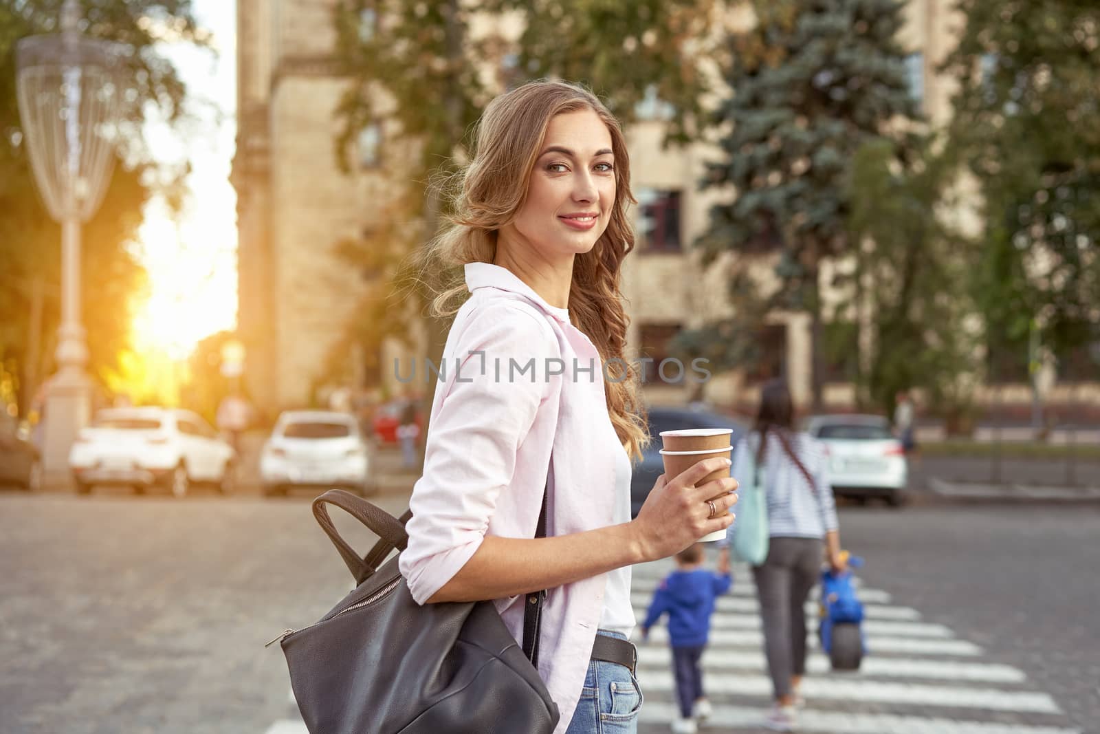 Businesswoman standing summer day city street pedestrian crosswalk near corporate building Business person Outdoors Successful european caucasian woman freelancer with coffee paper cap in hands