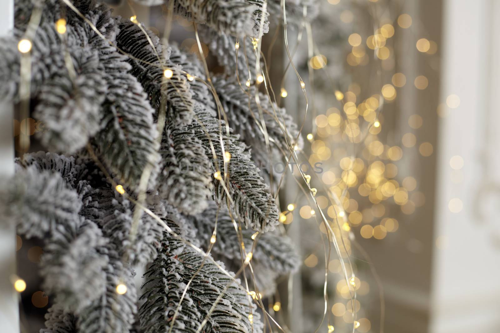 Christmas tree blur garland close-up New year background Decoration with snow and branch of Christmas tree