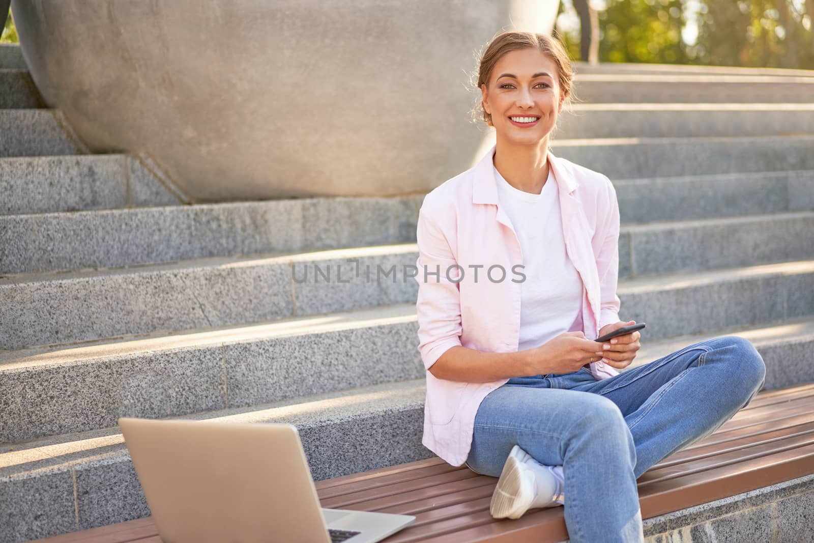 Businesswoman sitting stairs summer park using laptop and smartphone Business persone working remote. Outdoor. Successful Young european caucasian woman freelancer meeting online