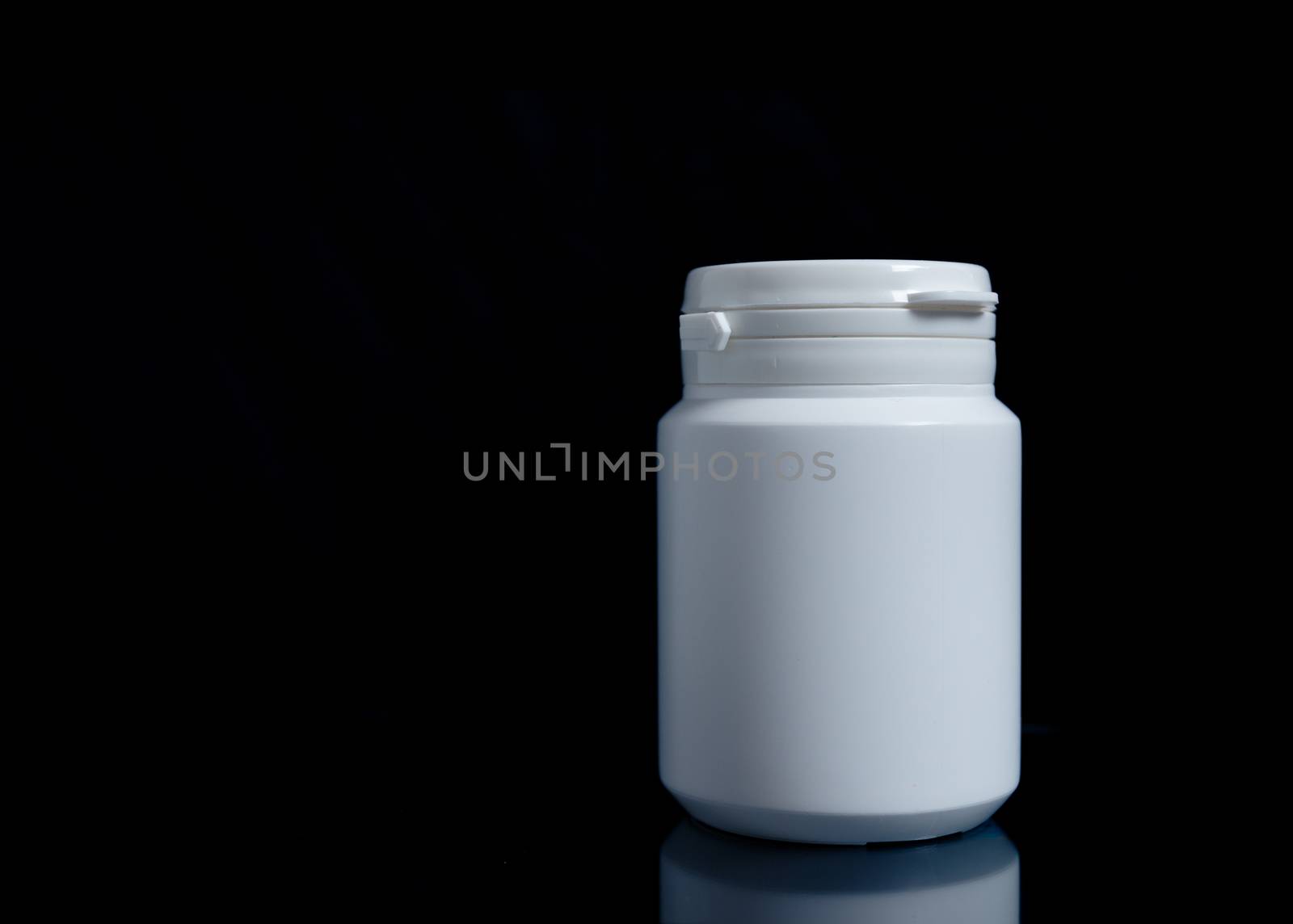 White medicine bottle on black background, medical concept