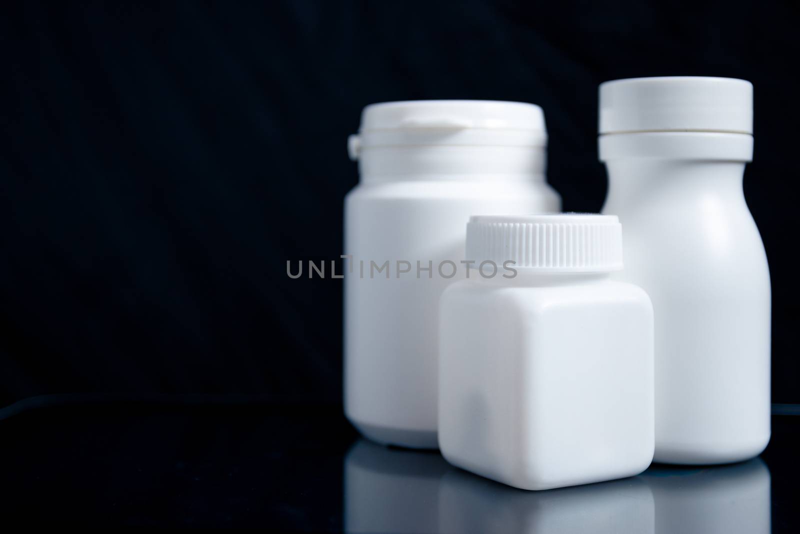 White medicine bottle on black background, medical concept