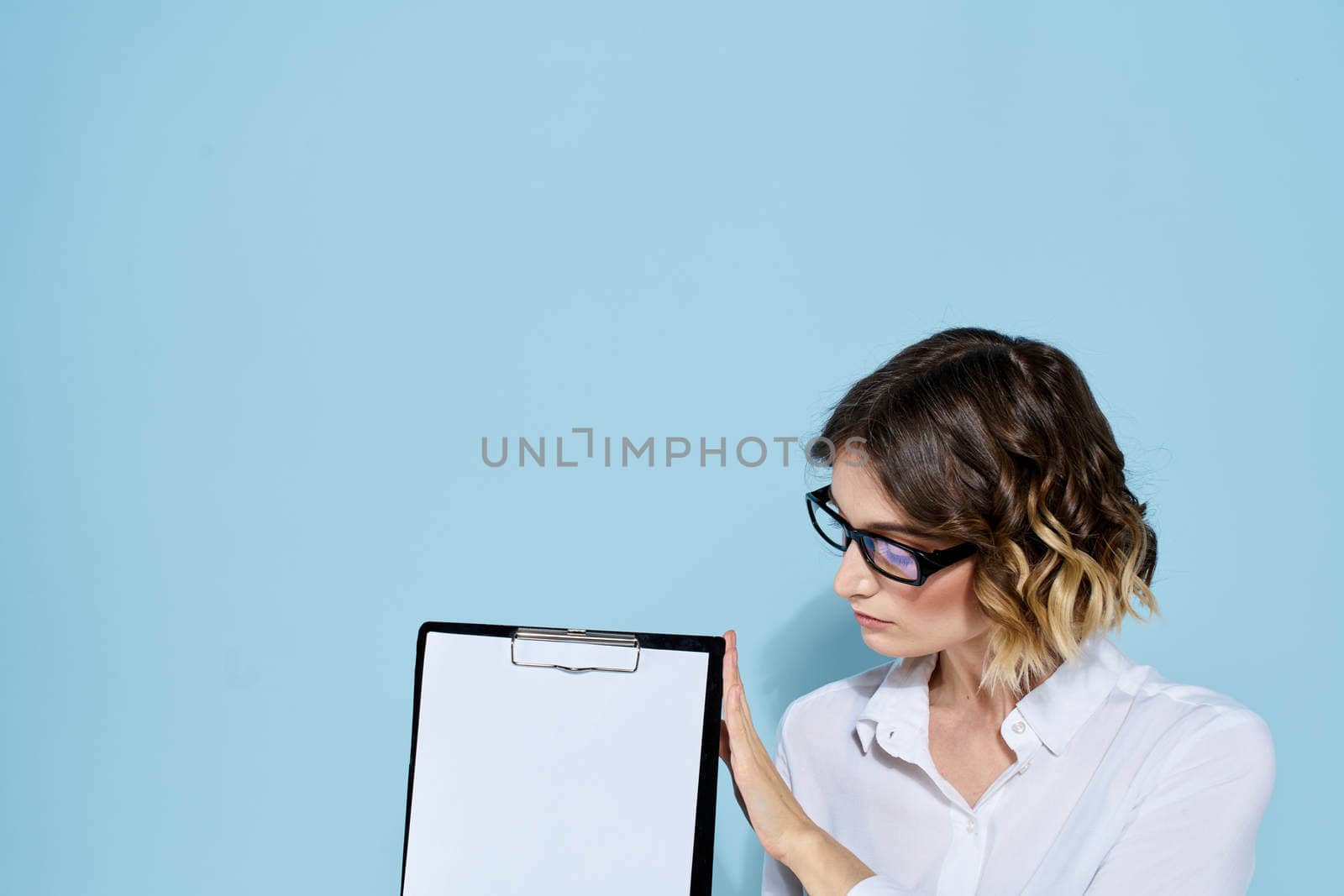 Business woman with documents in a folder on a blue background and in a light shirt glasses on her face. High quality photo