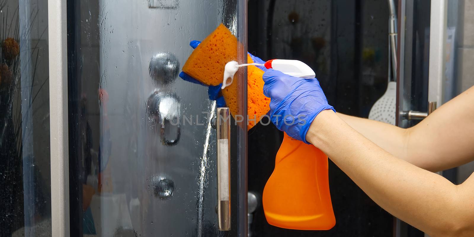 Cleaning of shower steam cabins from calcium deposits. Cleaning in the bathroom. hand in gloves with rag and detergent washing shower and glass by PhotoTime