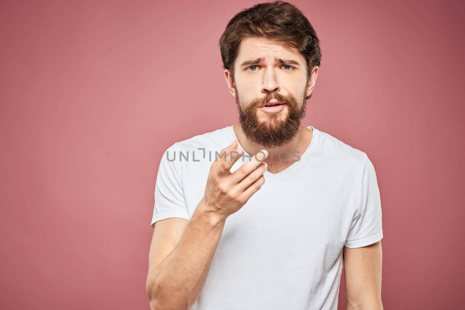 emotional man white t shirt sad facial expression pink background. High quality photo