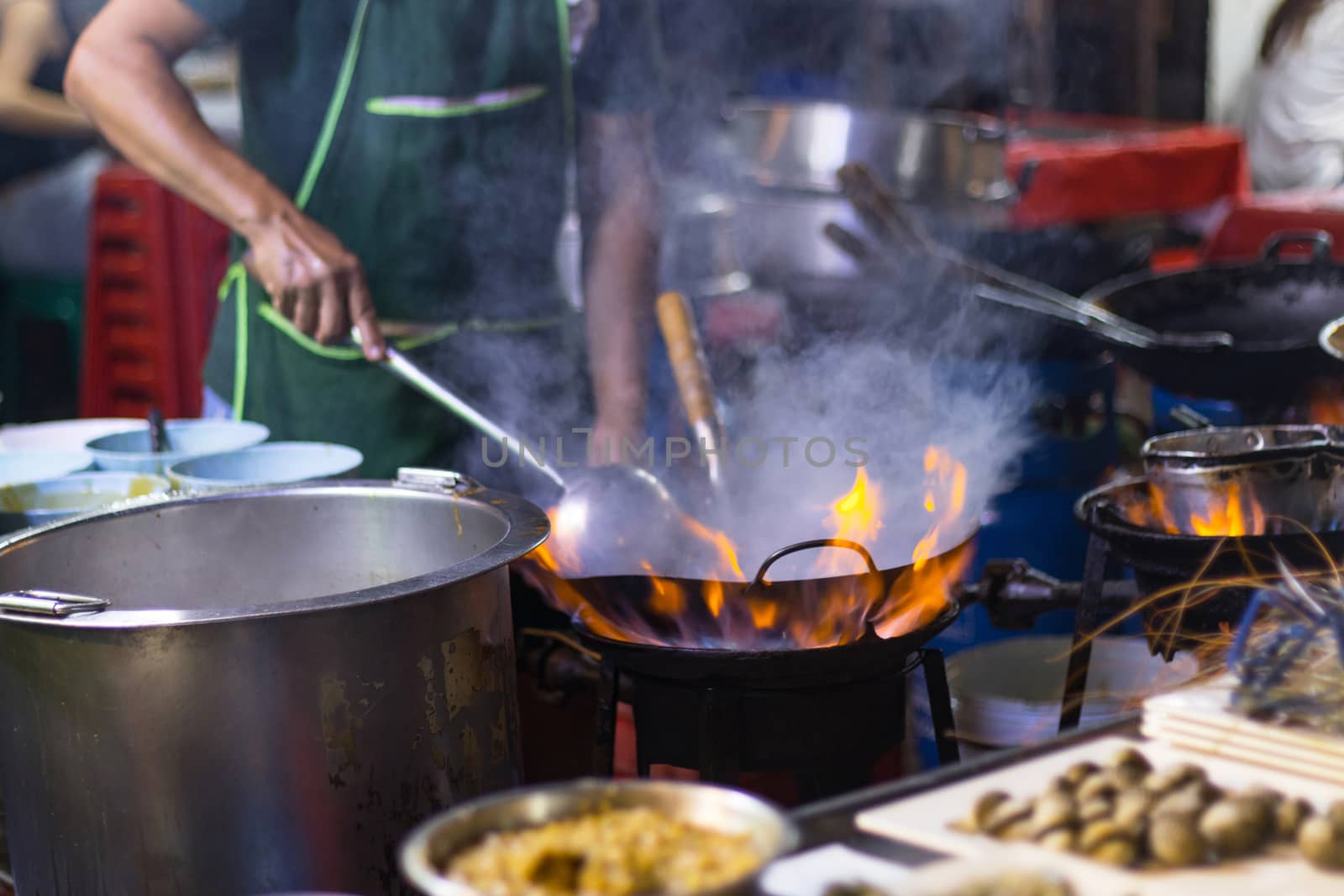 Street food in Bangkok Bangkok Thailand - Oct 24, 2020 :- Chef cooking with fire with frying pan on gas hob at yoawarat Bangkok Thailand.