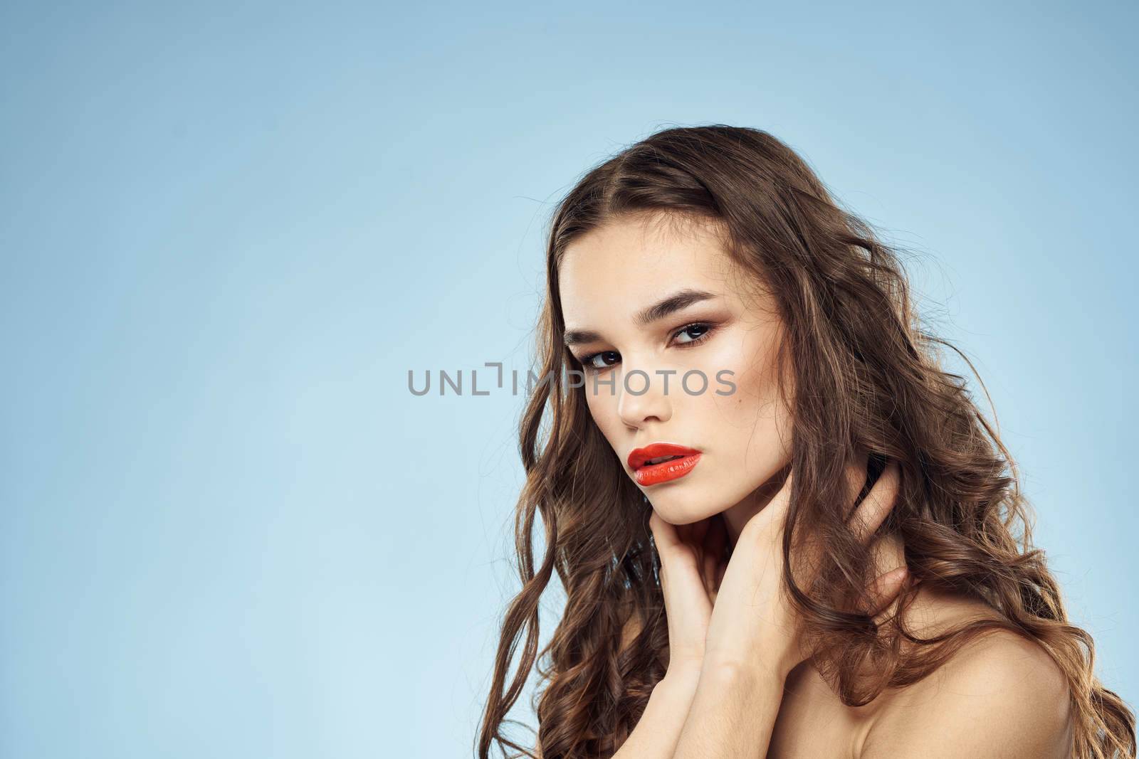 Beautiful woman naked shoulders hairstyle care bright makeup blue background. High quality photo