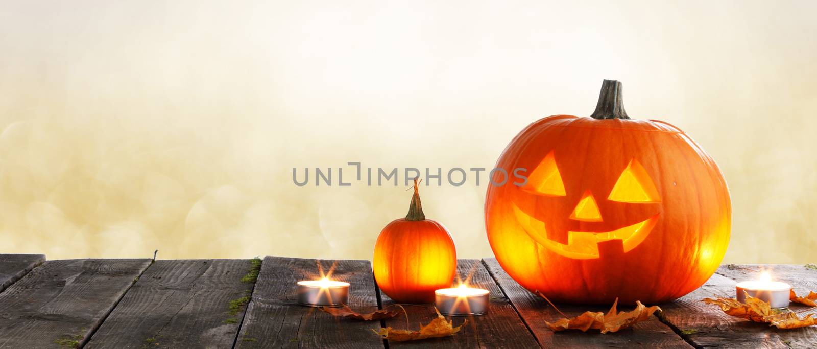 Magic halloween pumpkins and burning candles on golden bokeh lights background