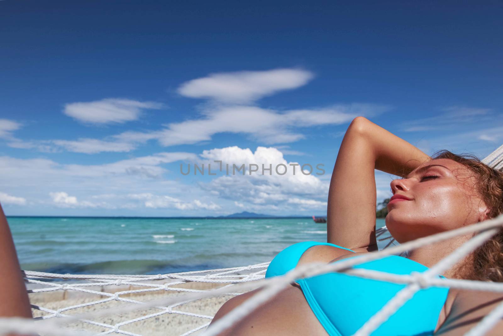 Girl in bikini relaxing in hammock on the beautiful paradise beach
