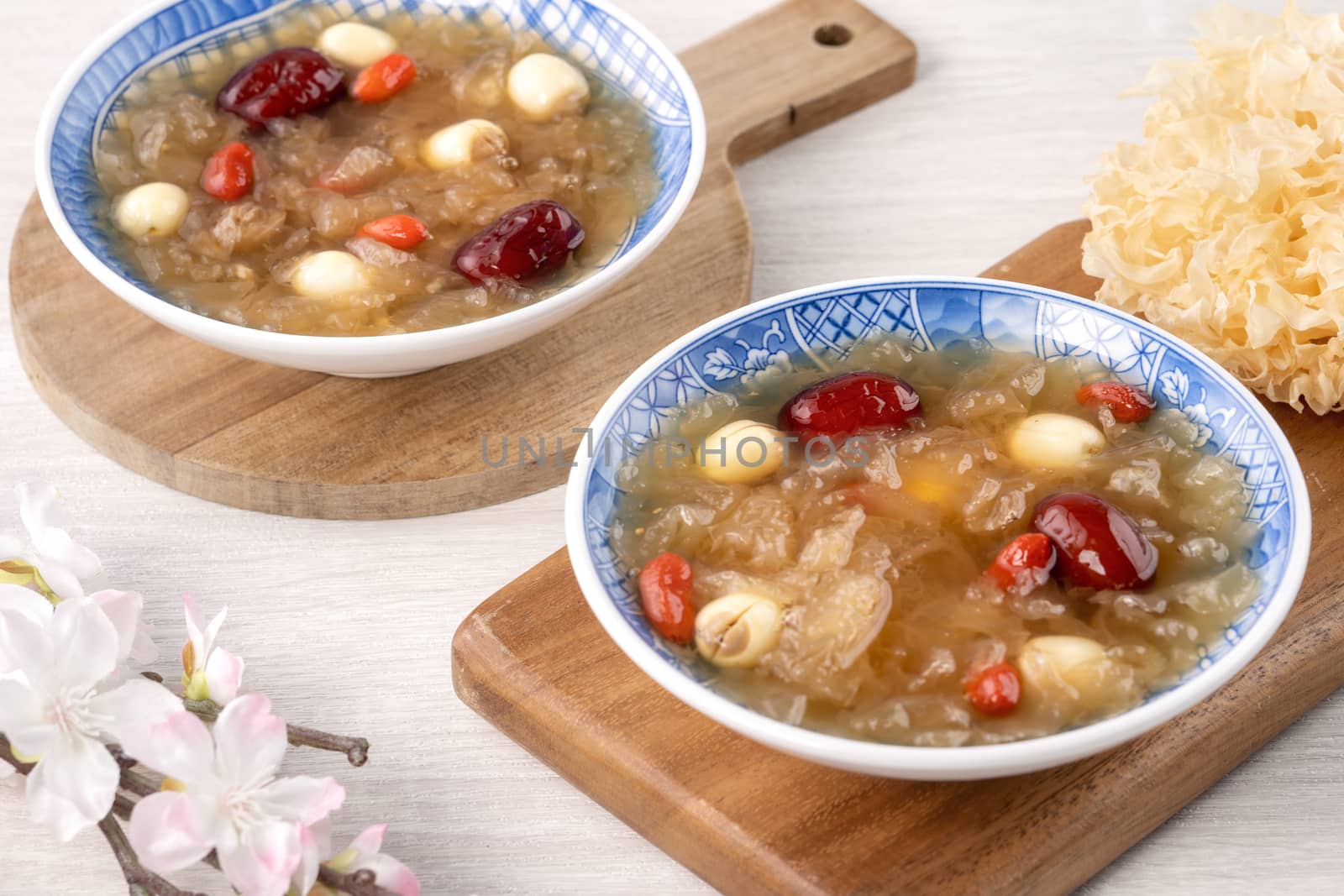 Close up of traditional Chinese sweet snow white fungus soup with lotus seed, red dates (jujube) and wolfberry (goji berry, gojiberry) on white background.