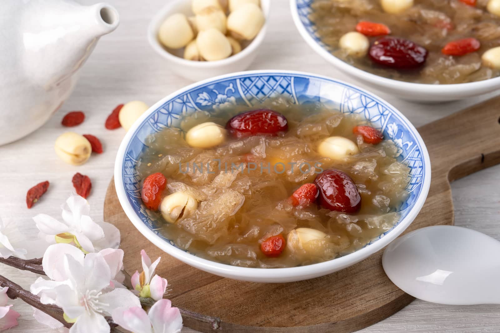 Close up of traditional Chinese sweet snow white fungus soup with lotus seed, red dates (jujube) and wolfberry (goji berry, gojiberry) on white background.