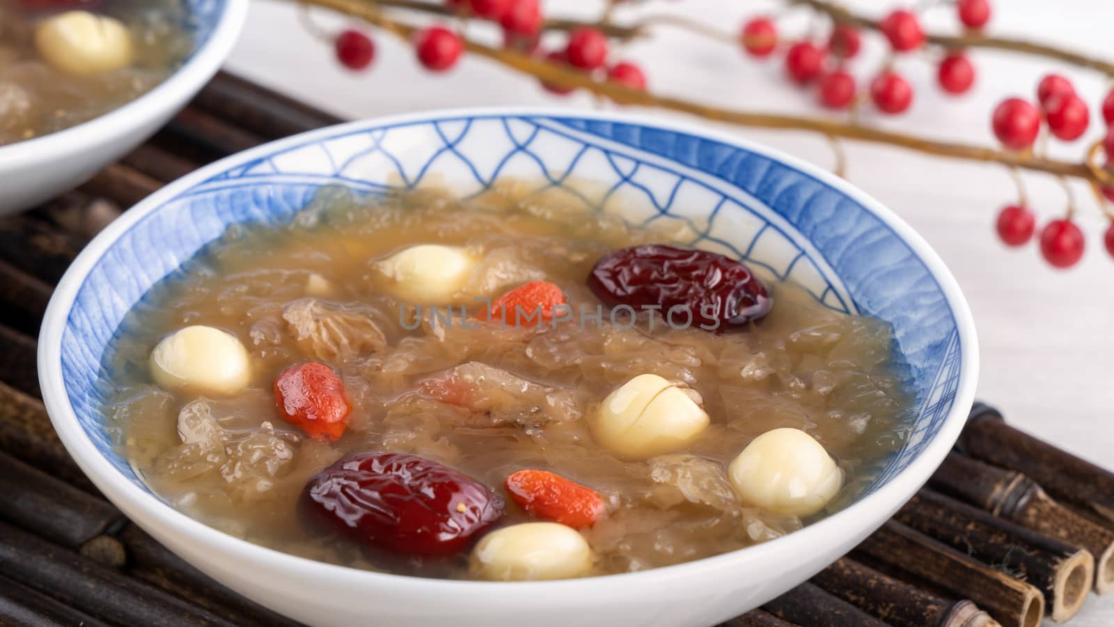 Close up of traditional Chinese sweet snow white fungus soup with lotus seed, red dates (jujube) and wolfberry (goji berry, gojiberry) on white background.