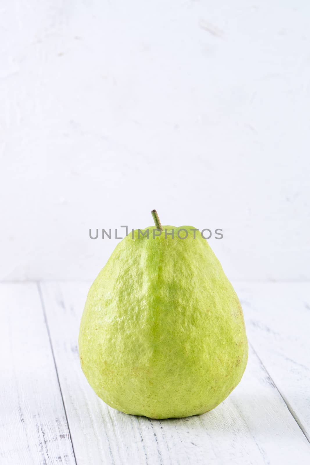 Delicious beautiful guava set with fresh leaves isolated on bright white wooden table background, close up.