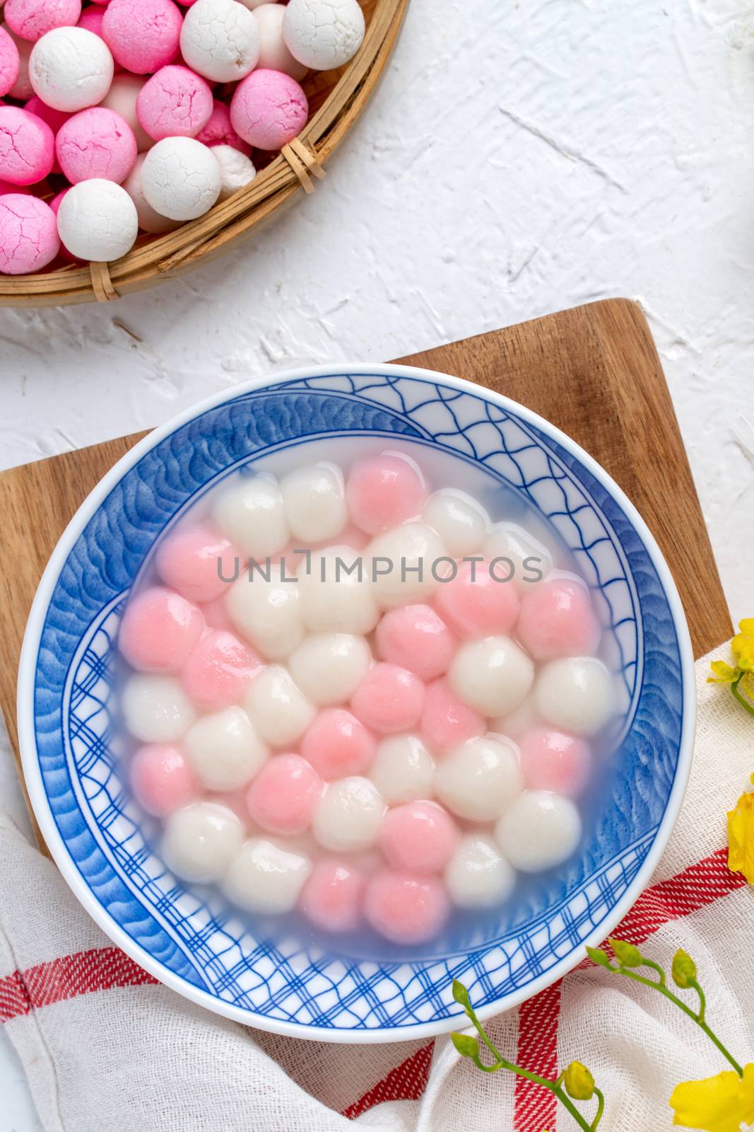 Top view of red and white tangyuan (tang yuan, glutinous rice dumpling balls) in blue bowl on white background for Winter solstice festival food.