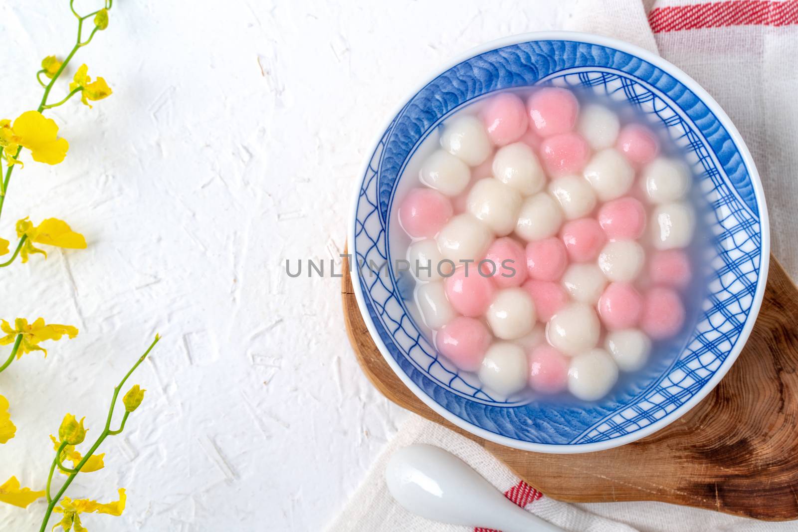 Top view of red and white tangyuan (tang yuan, glutinous rice dumpling balls) in blue bowl on white background for Winter solstice festival food.