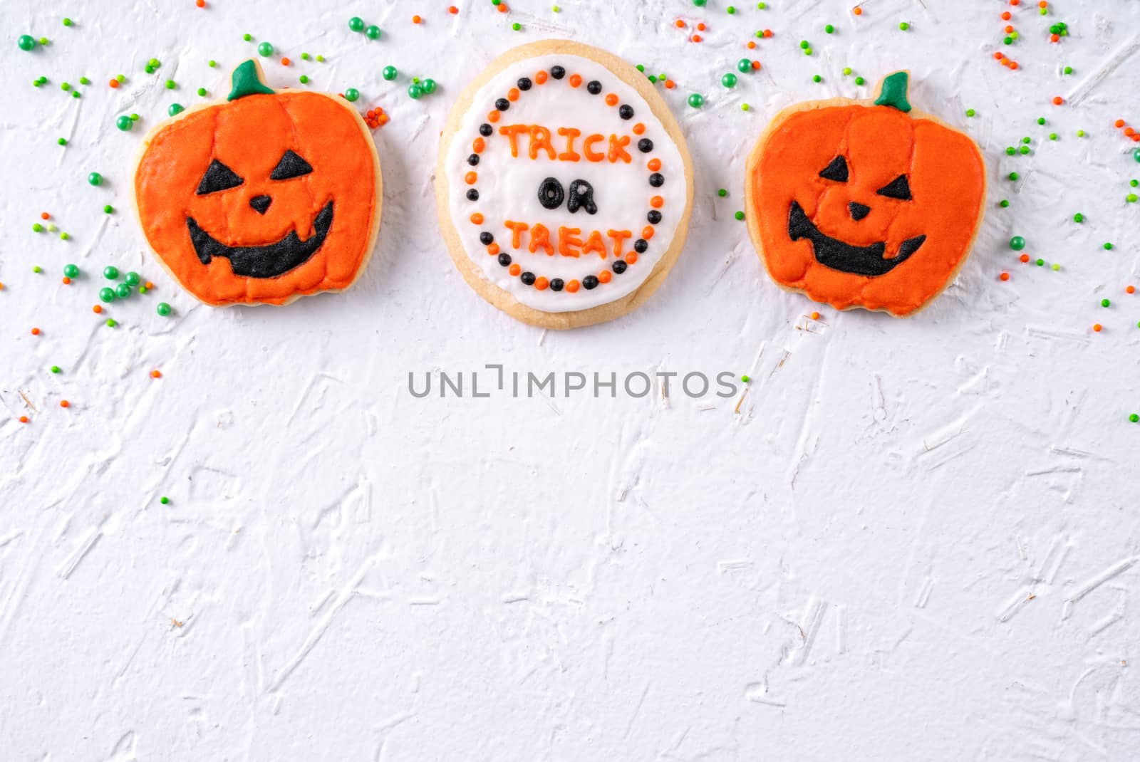 Top view of Halloween festive decorated icing gingerbread sugar cookies on white background with copy space and flat lay layout.