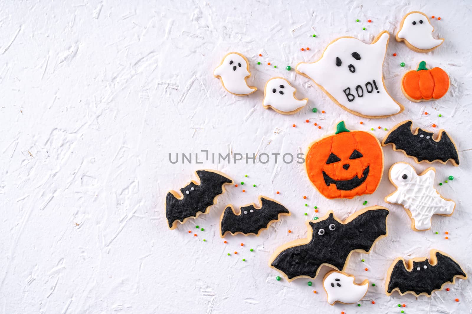 Top view of Halloween festive decorated icing gingerbread sugar cookies on white background with copy space and flat lay layout.