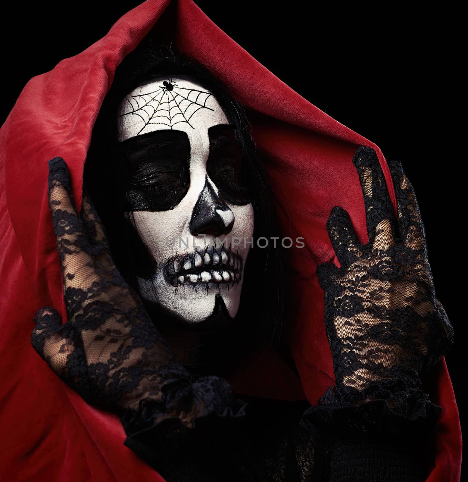 woman with make-up with a skeleton stands on a black background in a red cloak with a hood, fictional image for Halloween