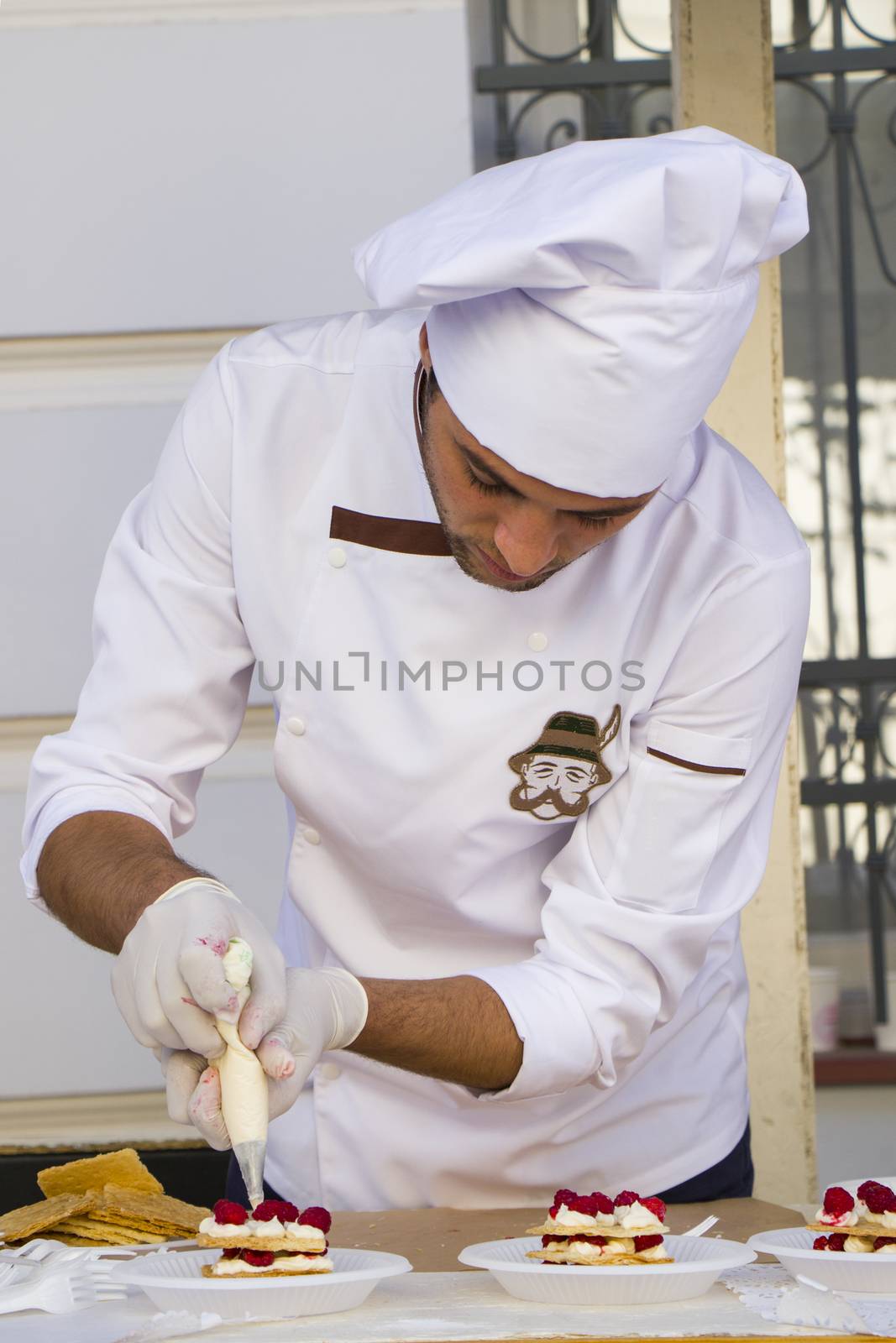 TBILISI, GEORGIA - OCTOBER 08, 2017: Confectioner chef cooking dessert scene, chef decorates cake and working in the street of Tbilisi on the city festival.
