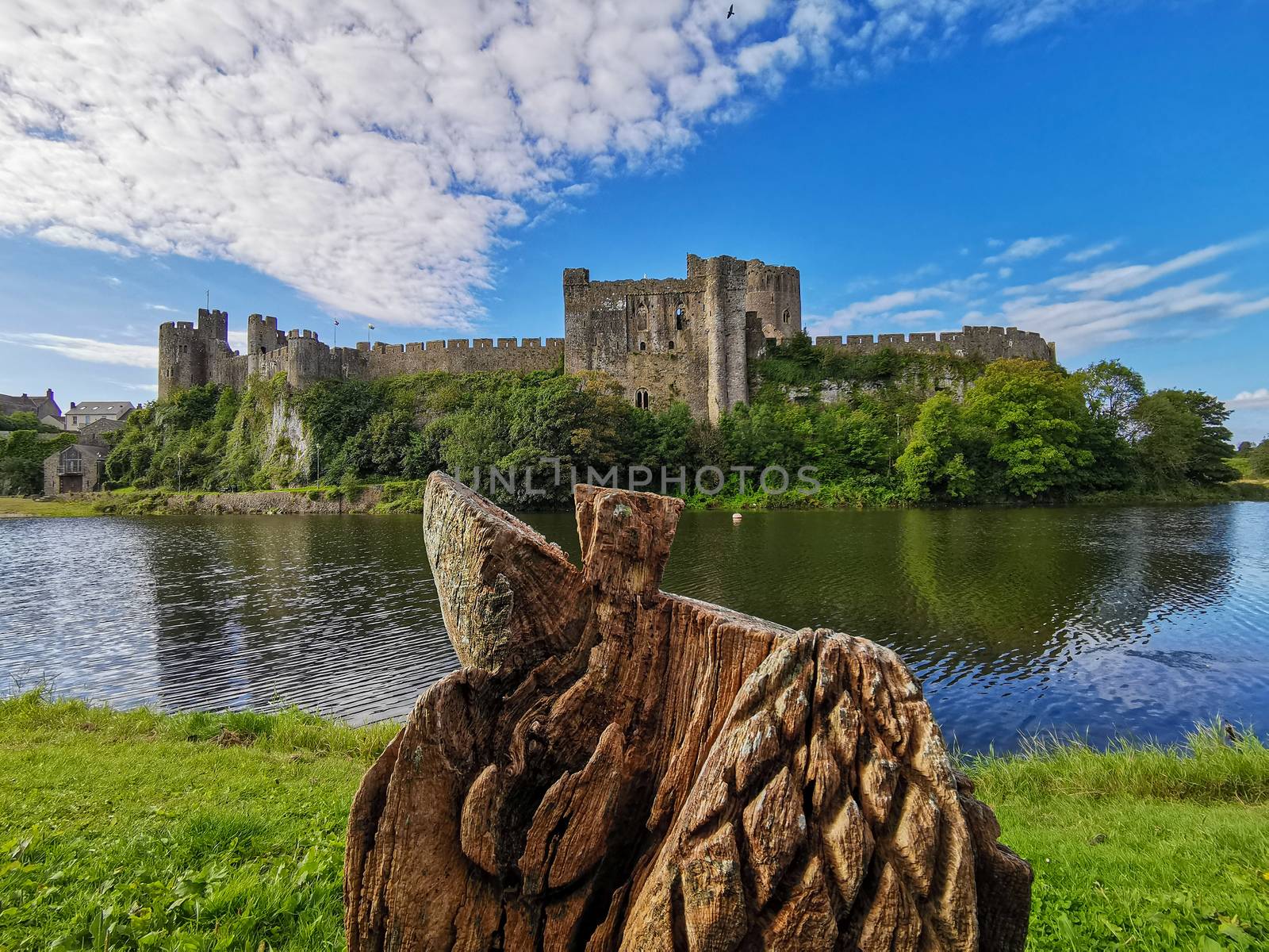 The medieval Pembroke Castle Wales surrounded by a moat and overlooked the market town of Pembroke. This fortress is an historical building and the start of the Tudor Dynasty. Blue skys and a wooden carving.