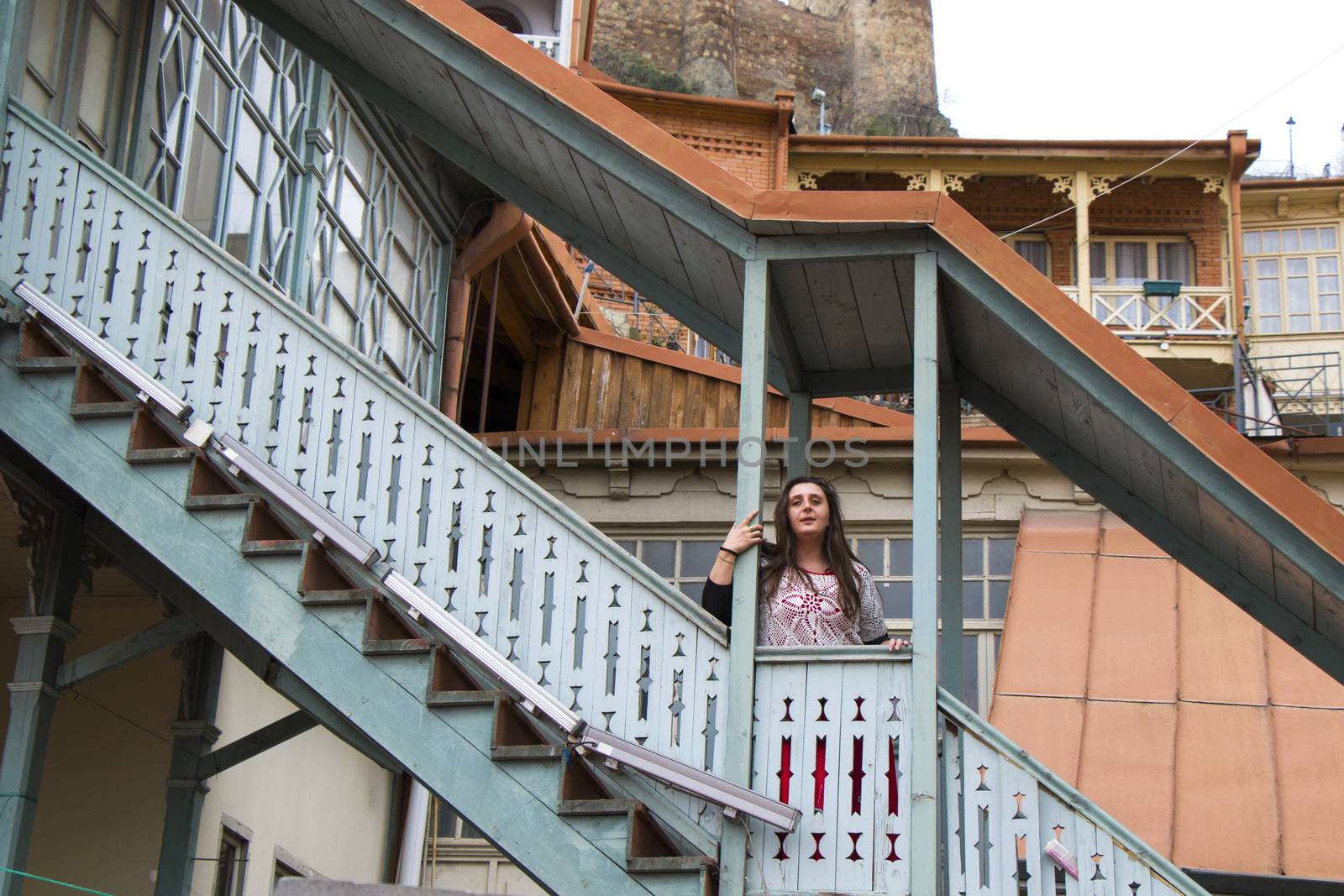 Young woman portrait, beautiful girl, pretty and cute girl and old famous balcony in Tbilisi. Urban travel scene.