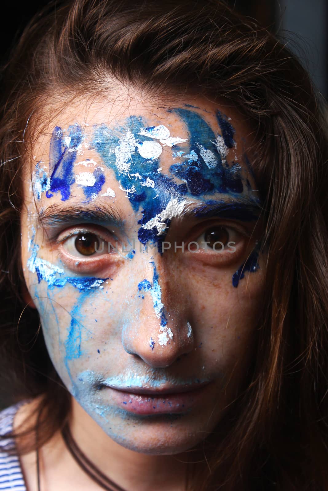 Painted face with acrylic blue and white colors. Young beautiful woman portrait, close-up photo.