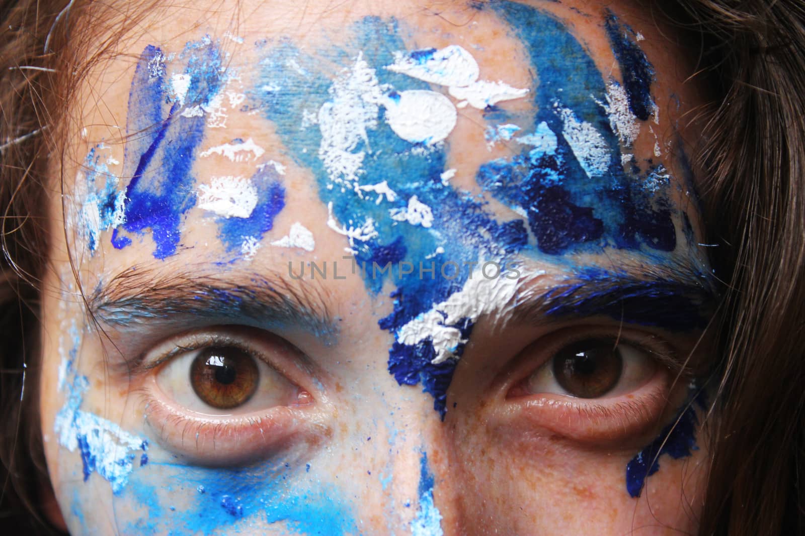 Painted face with acrylic blue and white colors. Young beautiful woman portrait, close-up photo.