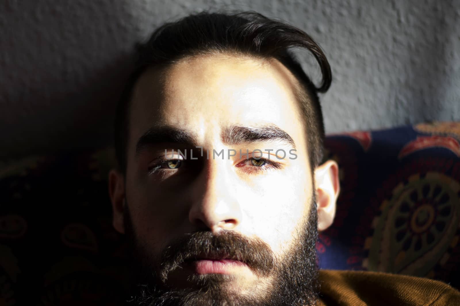 Handsome serious man portrait on the dark background, sunlight and room.