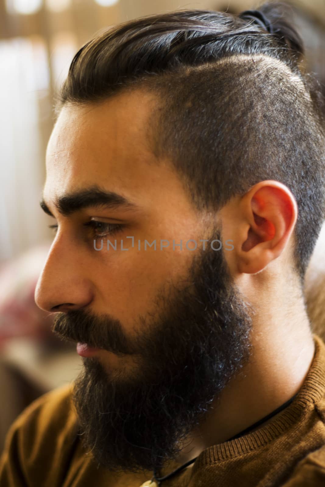 Handsome serious man portrait on the dark background, sunlight and room.