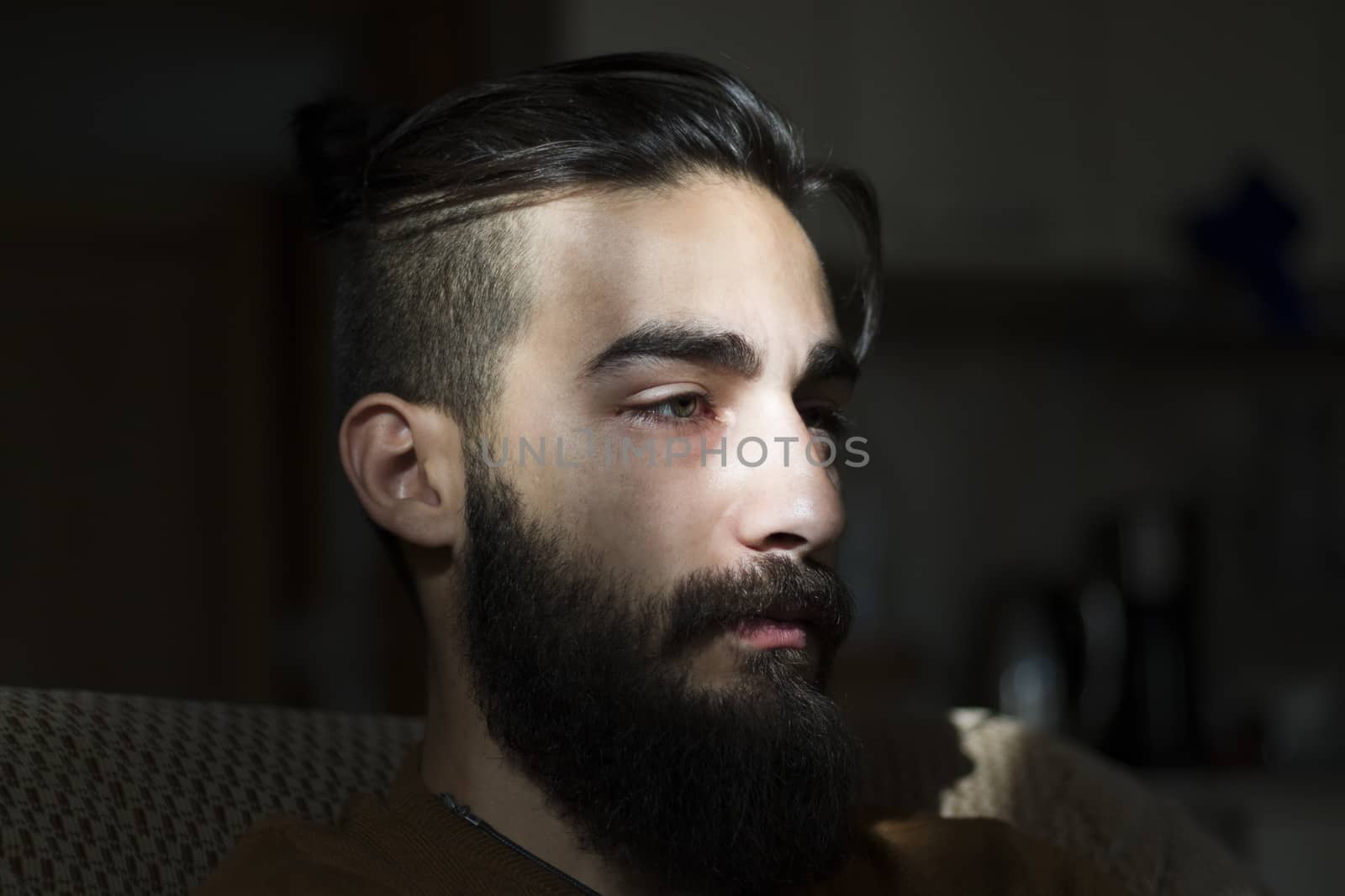 Handsome serious man portrait on the dark background, sunlight and room.