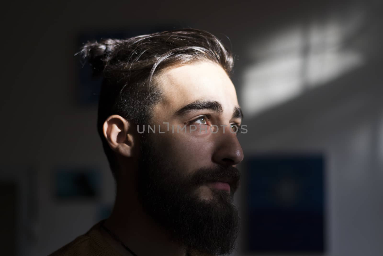 Handsome serious man portrait on the dark background, sunlight and room.