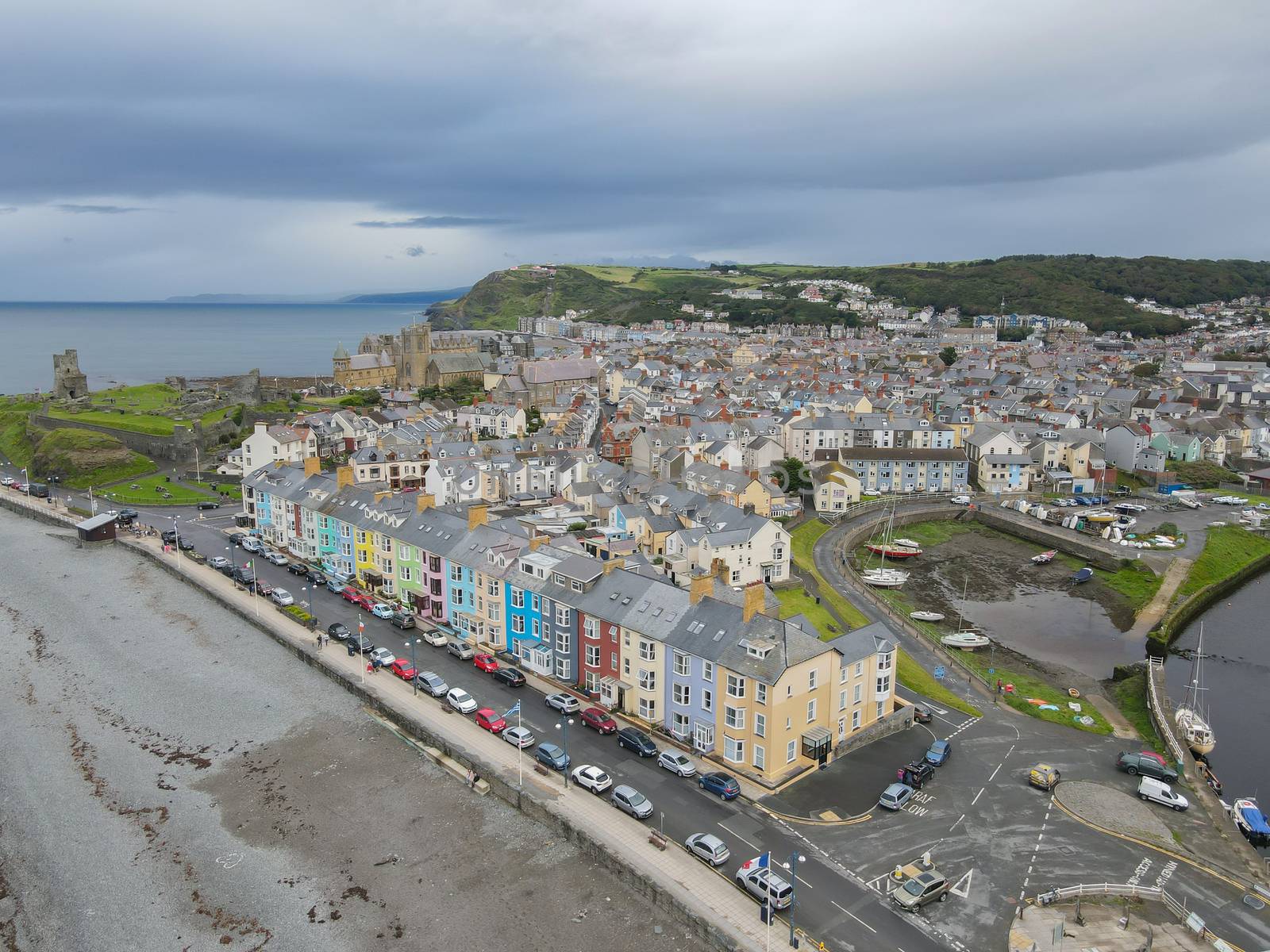 Colourful homes overlooking the sea at the South Beach Promenade in Aberystwyth, Ceredigion, Wales, UK, with the castle and town in the background.