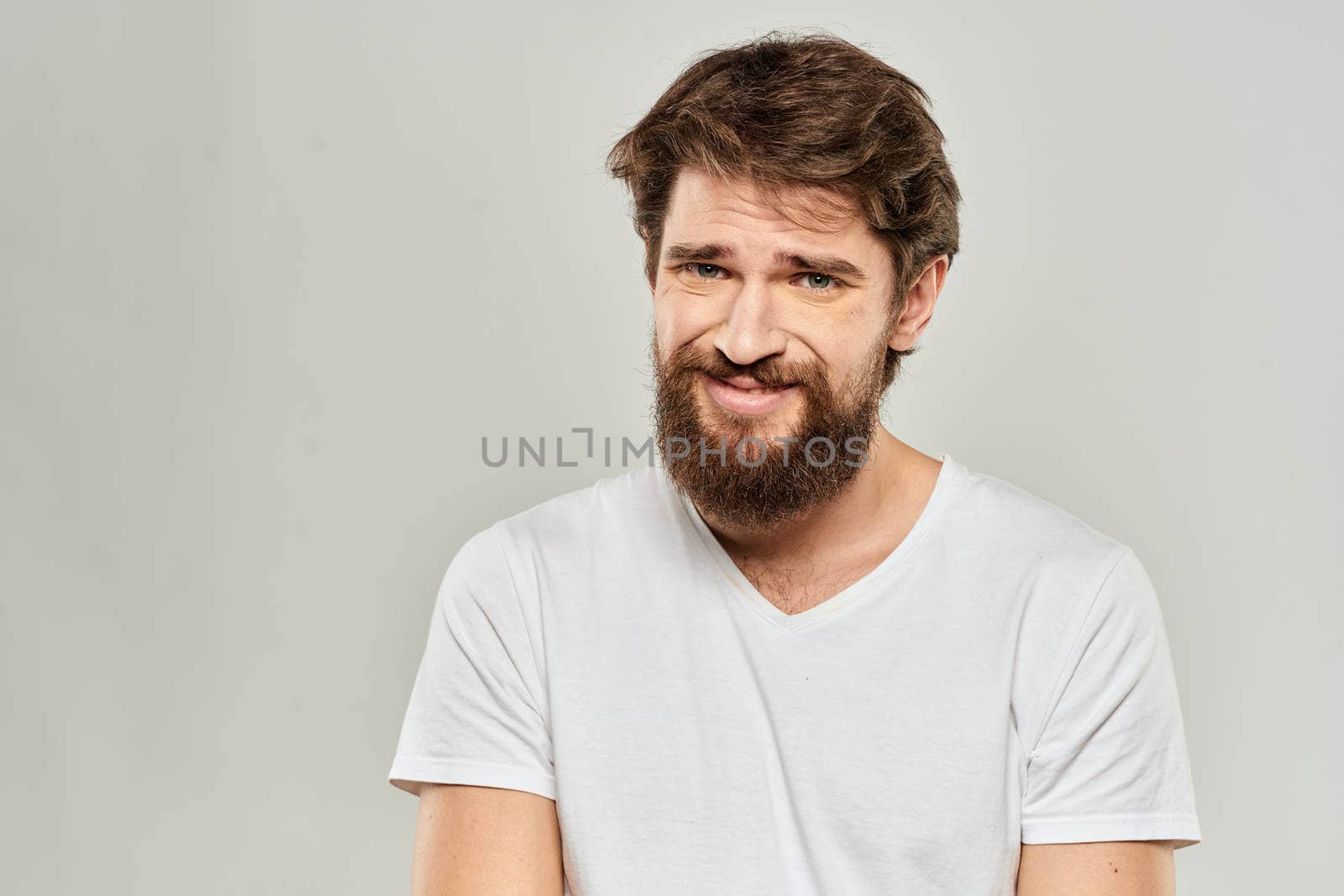 bearded man gesturing with his hands in a white t-shirt aggression light background. High quality photo